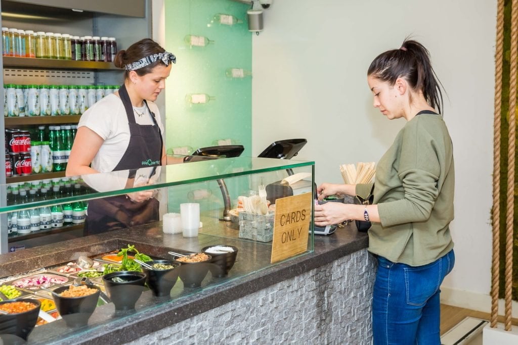 Un miembro del equipo de Poké Perfect en acción, preparando con pasión poké bowls frescos y ofreciendo un entorno de trabajo acogedor a los nuevos compañeros.